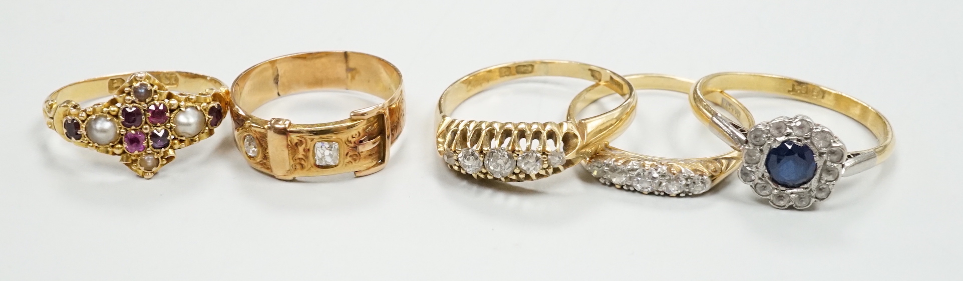 A Victorian 18ct gold and gem set dress ring, size I, three other 18ct and gem set rings and a yellow metal and diamond set buckle ring, gross weight 13.3 grams.